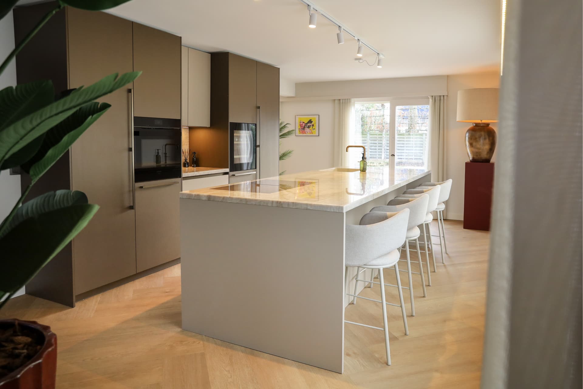 Binnen kijker Christian en Wendy.png Houten keuken met hoge kasten en een beige kookeiland met bar