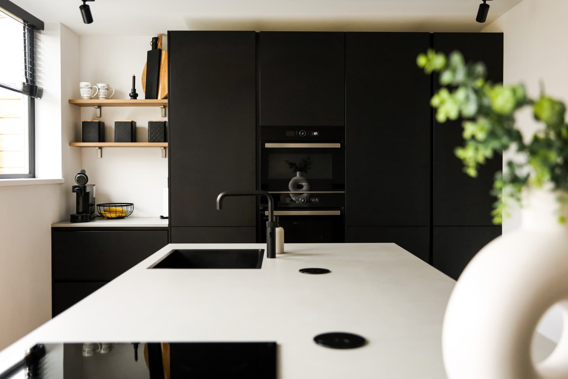 De keuken van Familie van Hooft_00015.jpg Zwarte keuken met hoge kasten een koffiehoek en een kookeiland met betonlook werkblad