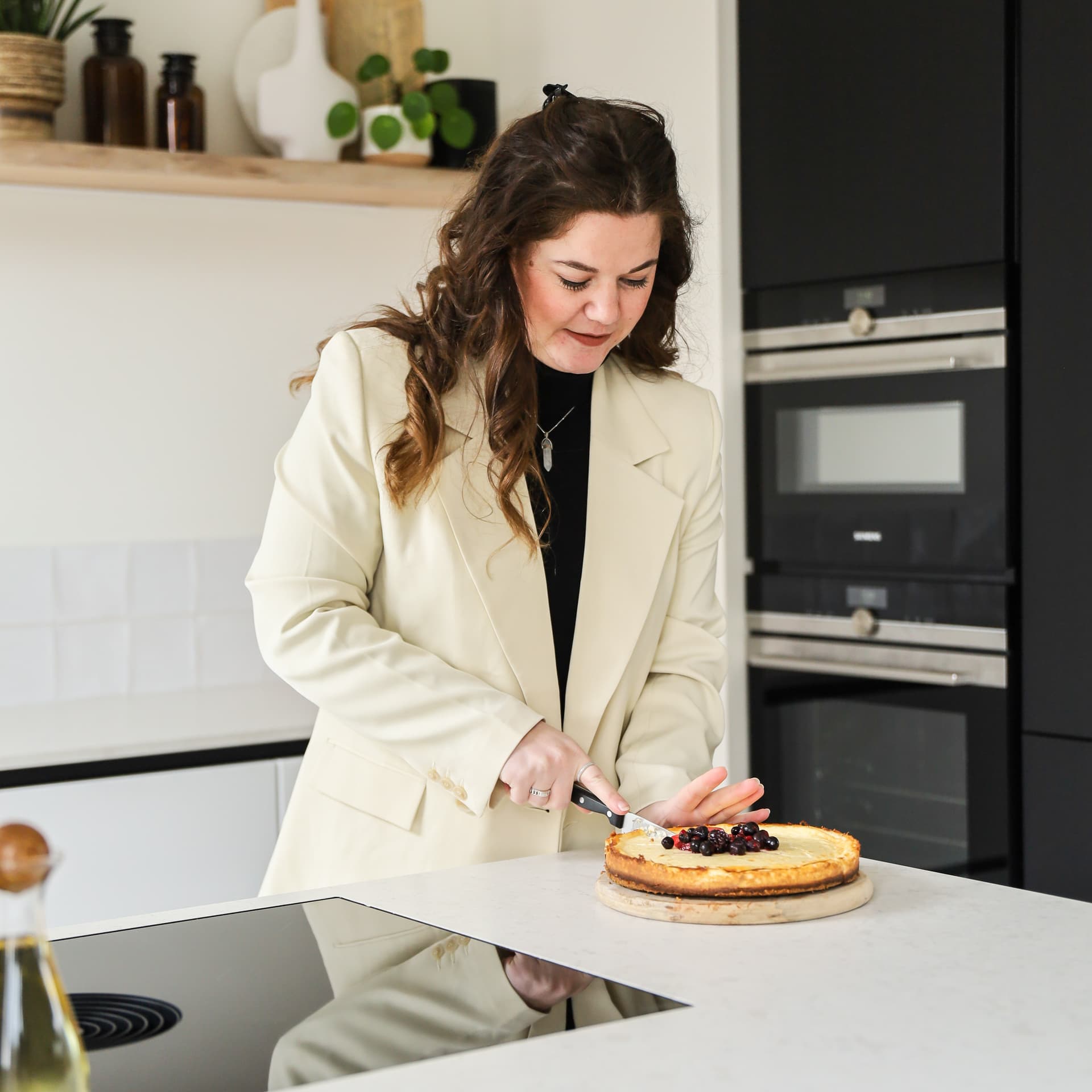 De keuken van Denise_30.jpg Jonge vrouw die taart aansnijd aan een kookeiland met grijs marmer werkblad