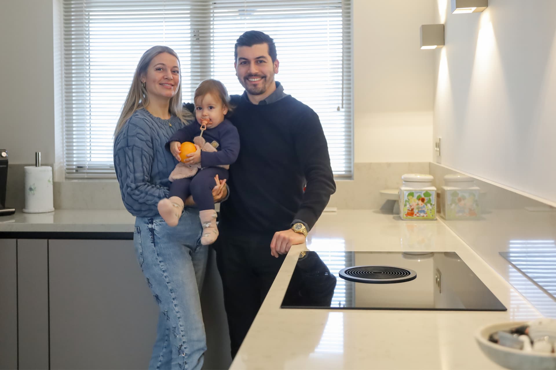 Headerbanner Binnenkijker Laura en Ozan (3000 x 2000 px).png Grijze hoekkeuken waar een een gezin poseert voor de foto