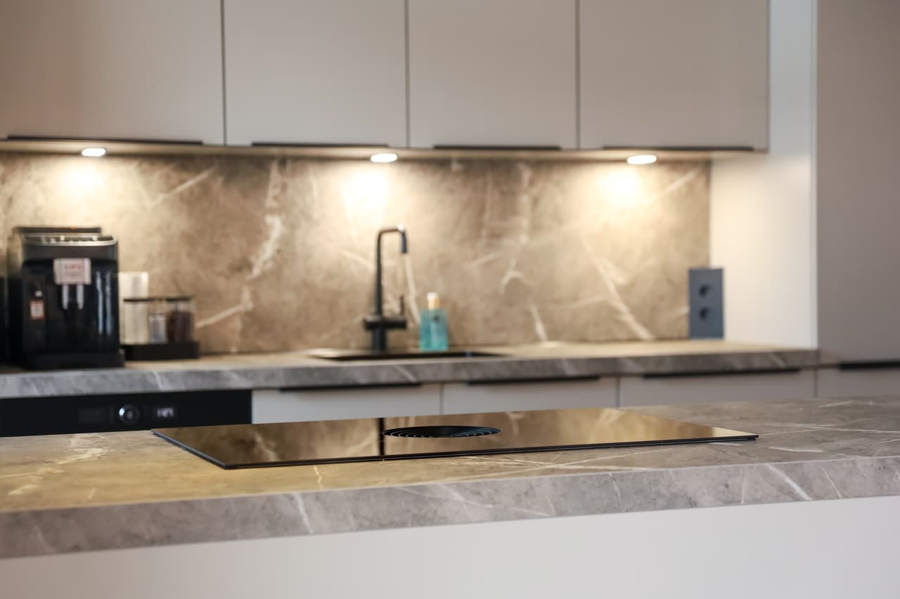 De keuken van Liza en Björn00005.jpg Beige schiereiland keuken met bruin marmer keukenblad en wand
