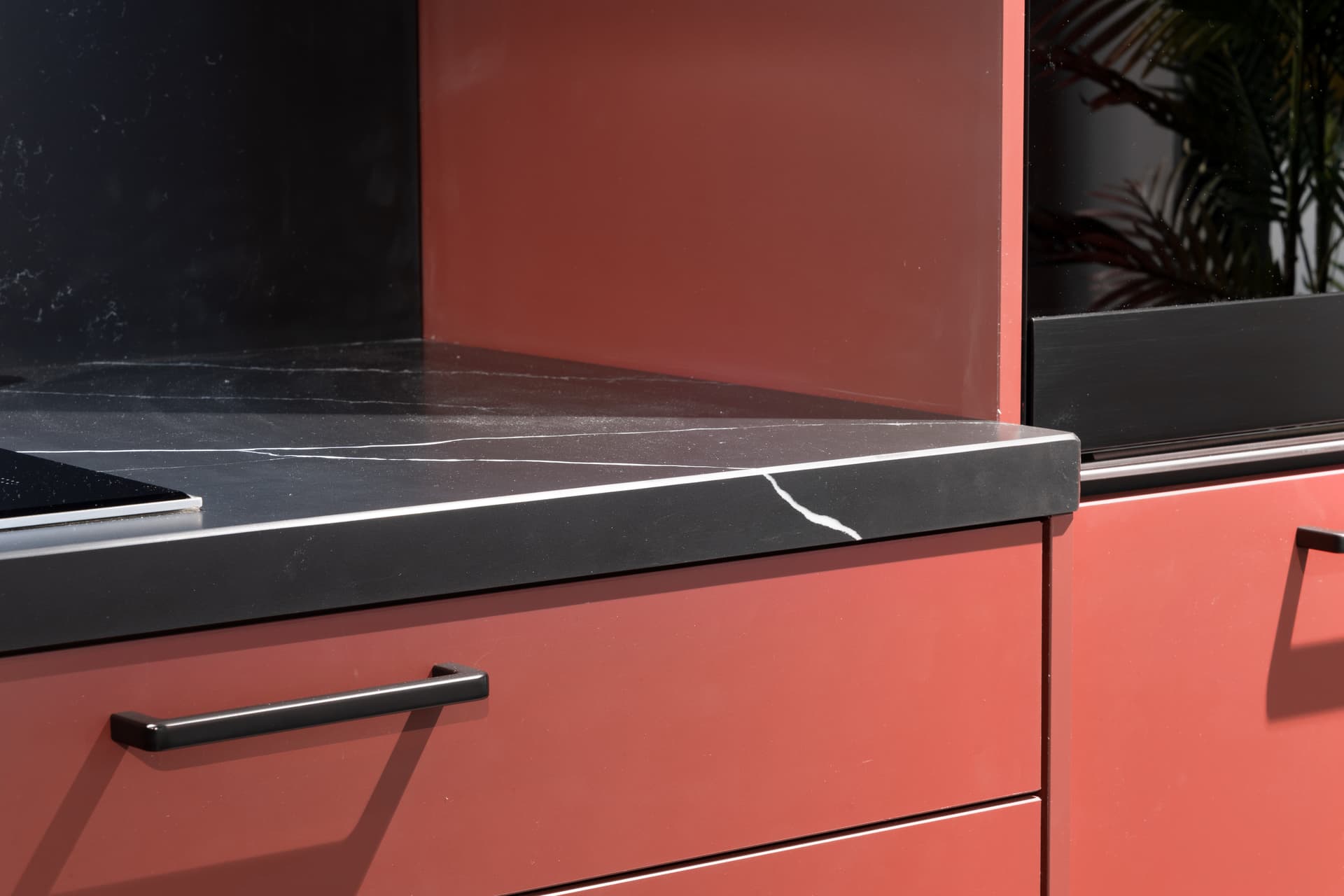 Kooi236_K_keukenconcurrent_Kaatsheuvel_XDetail_4-1.jpg Rode keuken met een zwart marmer werkblad en keukenwand